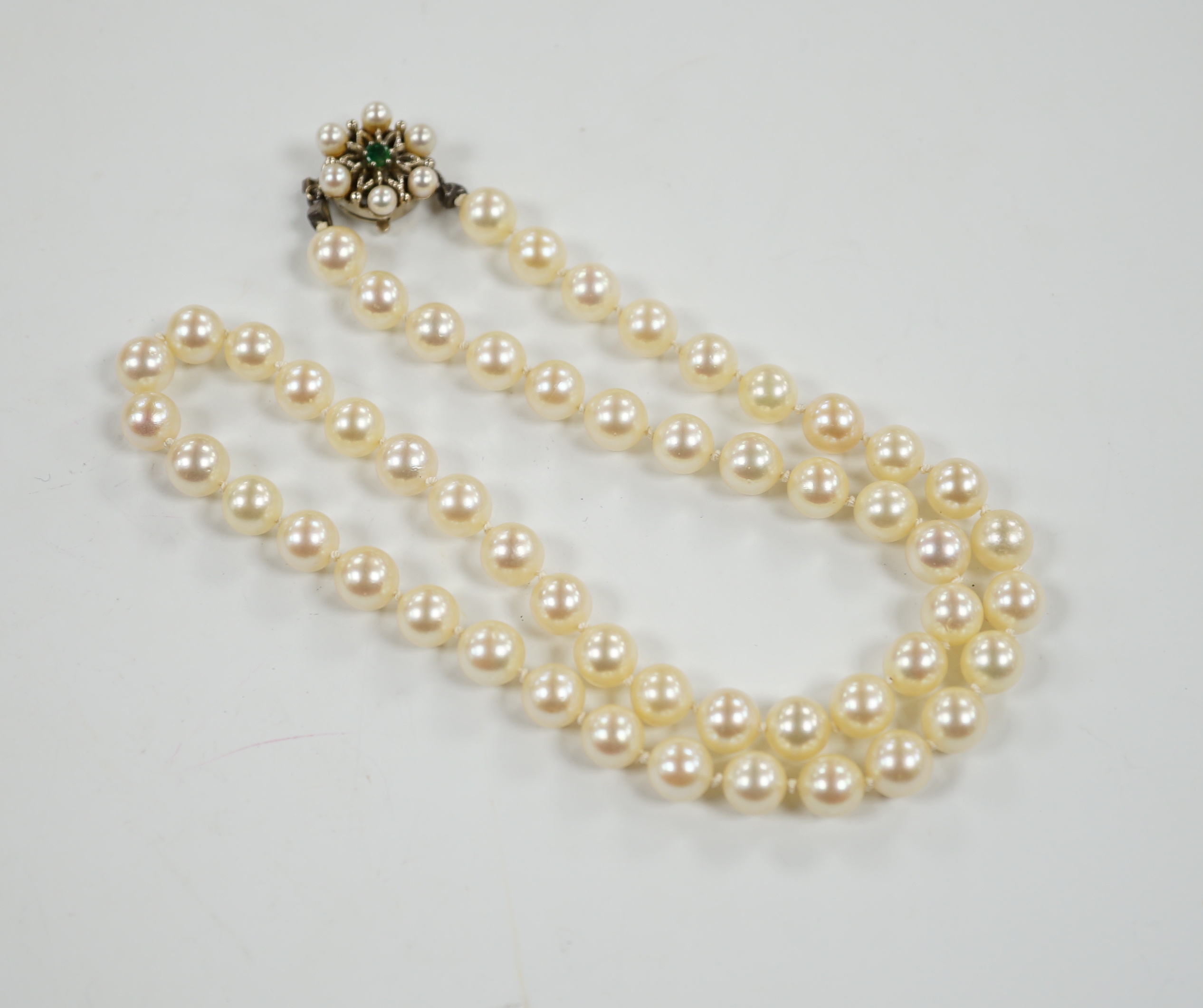 A single strand cultured pearl necklace, with cultured pearl and emerald set 585 yellow metal clasp, 49cm.